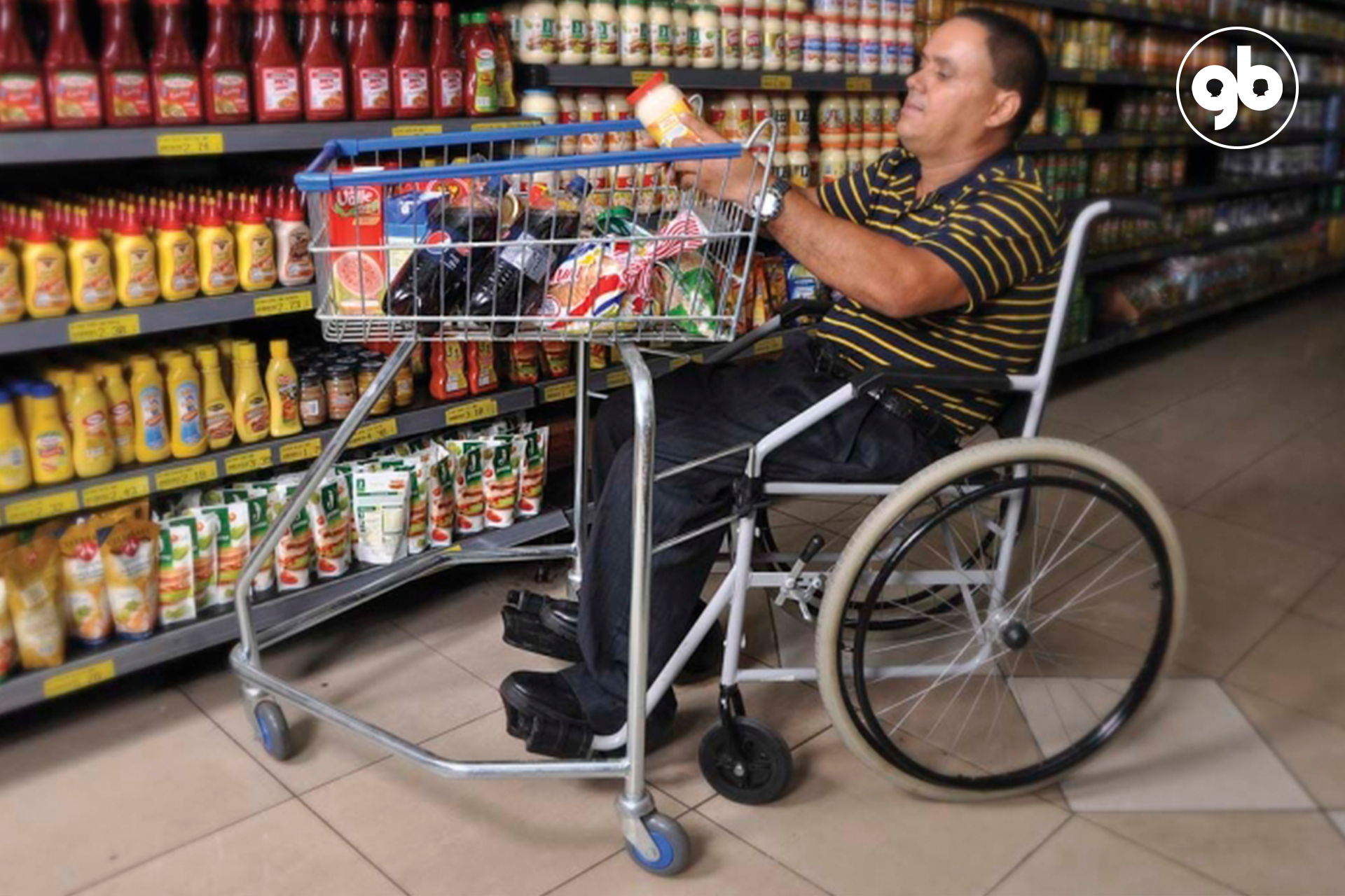 homem de pele parda em cadeira de rodas faz compras em supermercado com carrinho adaptado